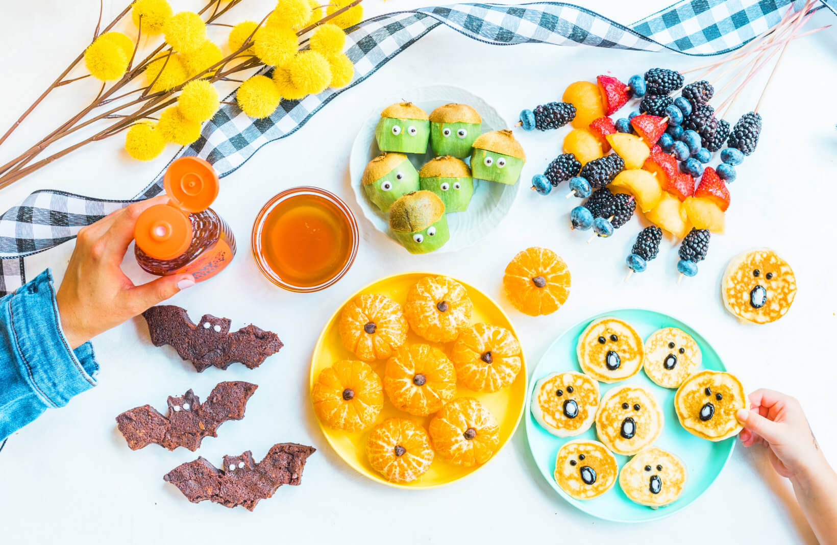 A colorful snack spread with fruit, crackers, and a bottle of Nate’s honey, crafted into playful, kid-friendly shapes.