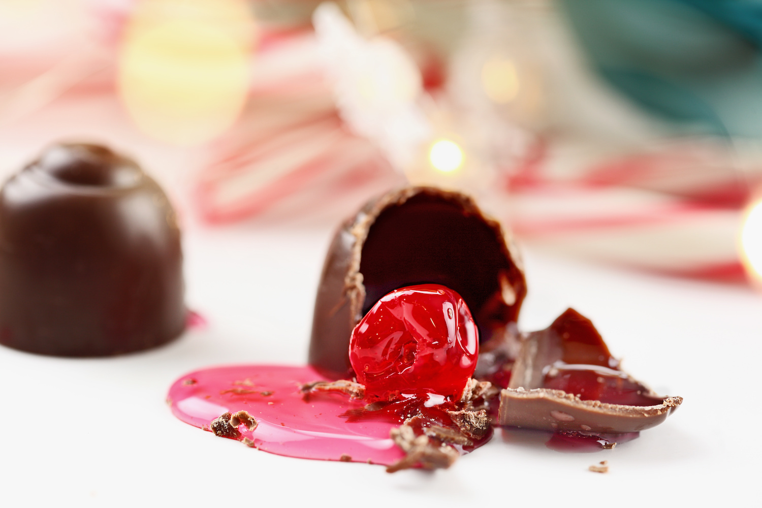 A cracked chocolate cherry cordial with bright syrup on a festive backdrop.