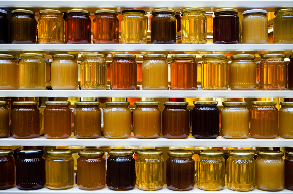 Rows of honey jars displaying various shades of amber.