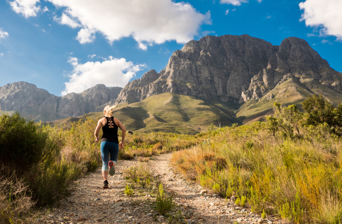 Runner on a trail with mountains in the background.