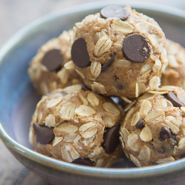 Oatmeal chocolate chip energy balls in a metal bowl on a textured surface.
