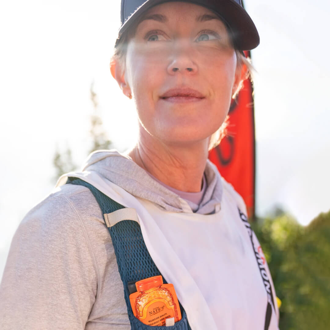 Athlete wearing outdoor gear with a Nate’s Honey Mini pouch tucked into their vest pocket,