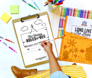 Child coloring bee activity sheet, surrounded by crayons and educational cards.