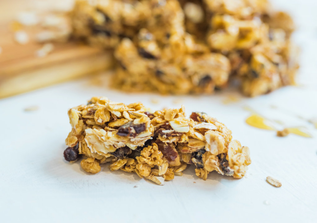 Close-up of chewy granola bars with oats and honey on a white surface.