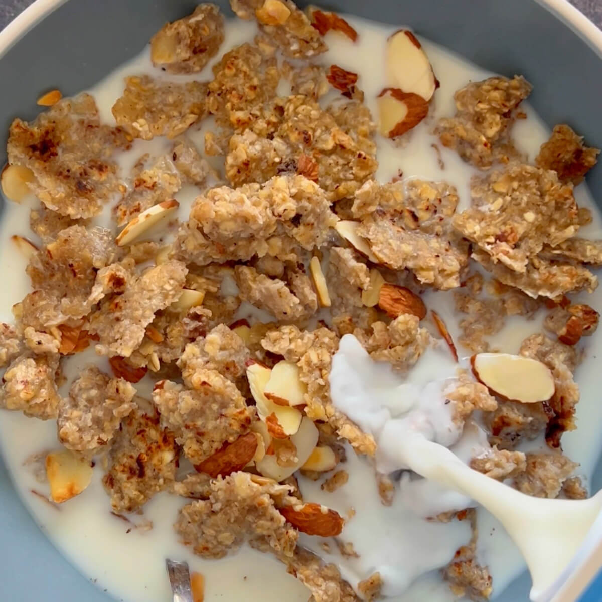 Bowl filled with homemade vanilla granola cereal with milk being poured into bowl.