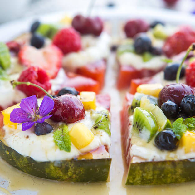 Grilled watermelon slices topped with fresh berries, edible flowers and honey drizzle.