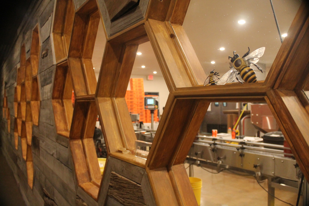 Decorative honeycomb wall with bee figure in a honey production facility. Decorative honeycomb wall with bee figure in a honey production facility.