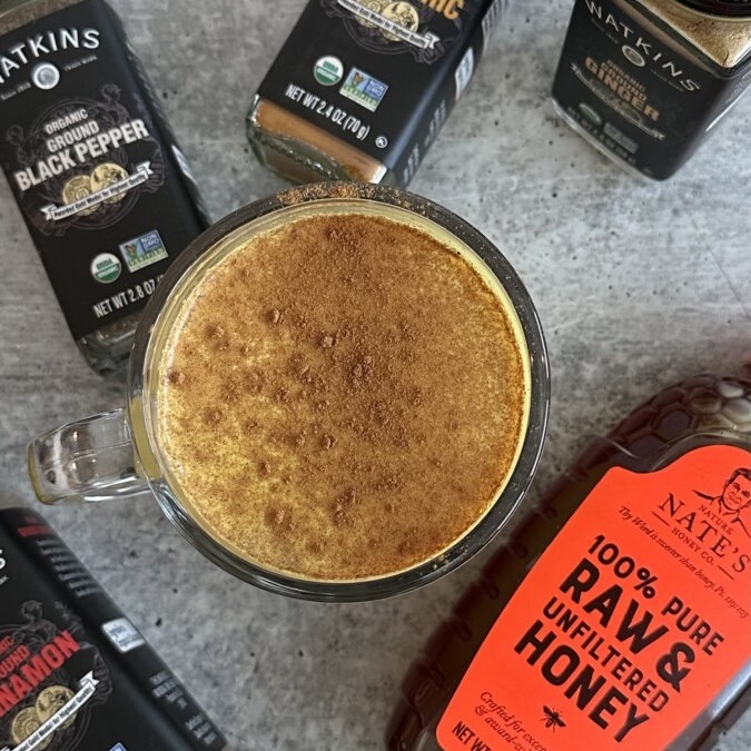 A spiced latte surrounded by Watkins organic spices and Nate's classic honey.