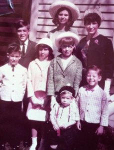 A vintage family portrait with seven members, featuring various outfits, evoking a sense of nostalgia.