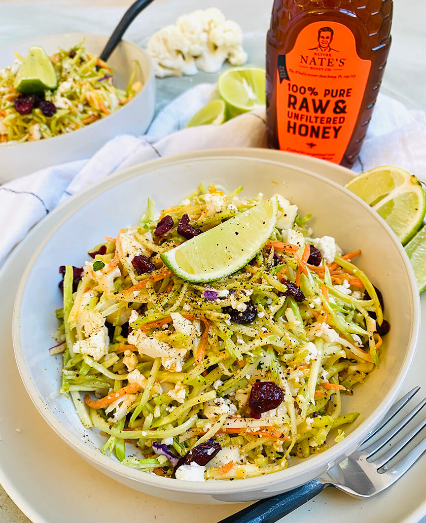 Zesty raw veggie salad with lime and a bottle of Nate's raw honey in the background.