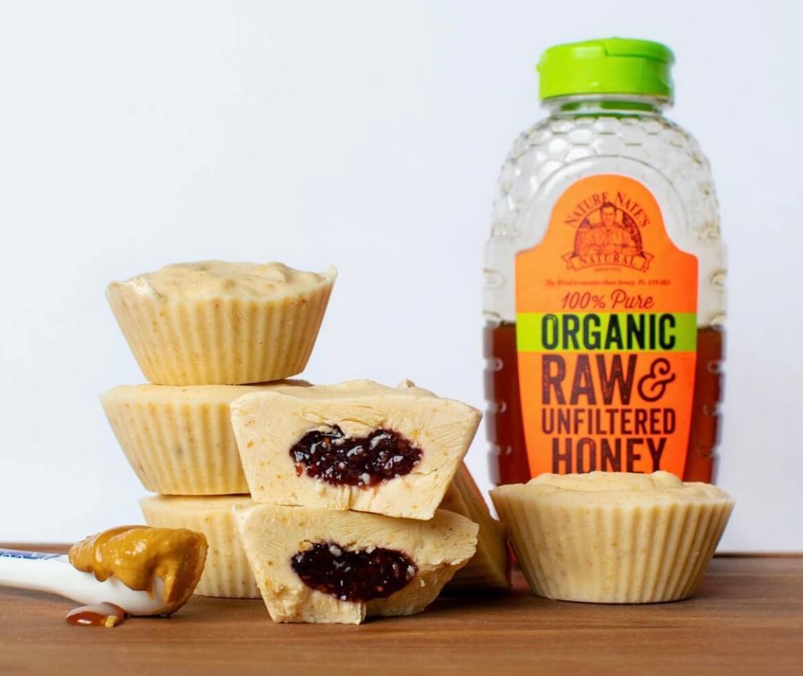 Peanut butter and jelly candy cups with a bottle of Nate’s organic raw & unfiltered honey.