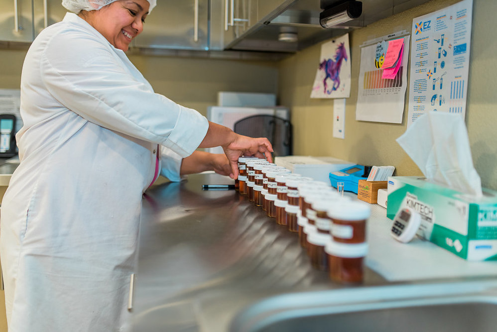 Worker arranging jars of honey in a testing facility.