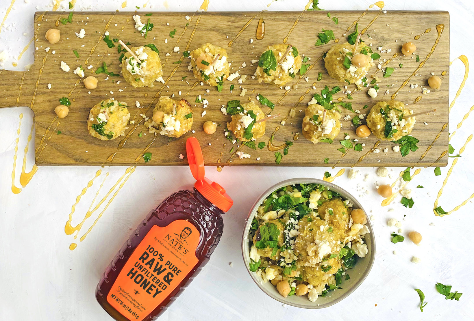 Jalapeno and honey meatballs on a board with honey drizzle and a bottle of Nate’s honey.