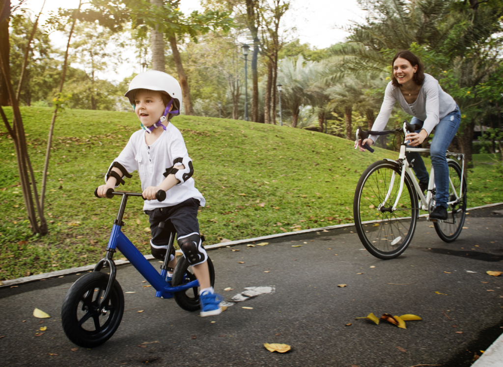 Child on a small bicycle and woman on bicycle on a park path. Child on a small bicycle and woman on bicycle on a park path.