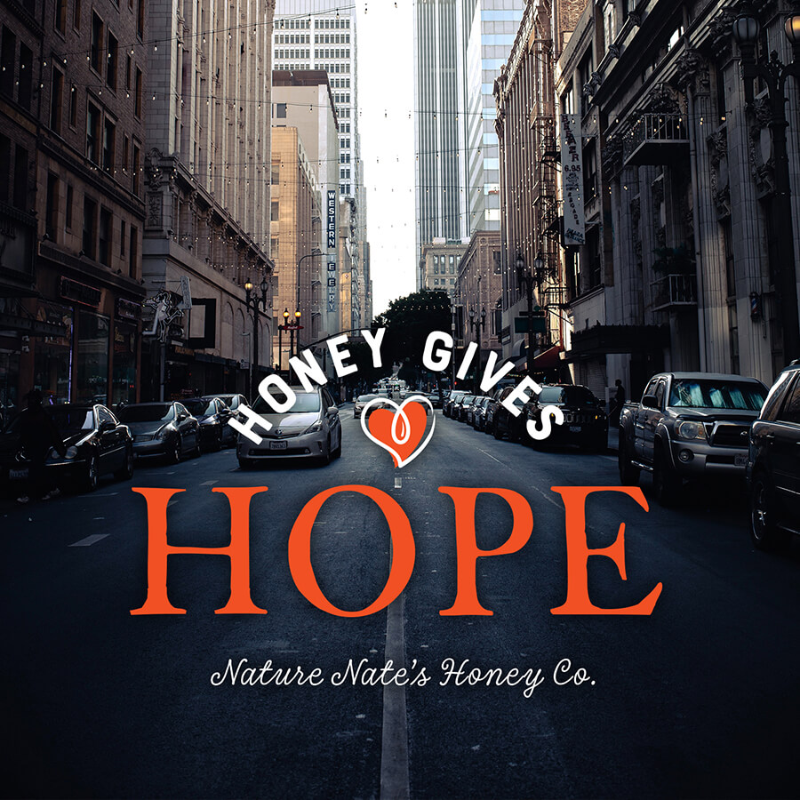 A city street with the phrase Honey Gives Hope, and a heart above Hope, by Nature Nate's Honey Co.