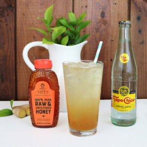 Iced honey-sweetened beverage with lime, Topo Chico and a Nate's honey bottle on a wood backdrop.