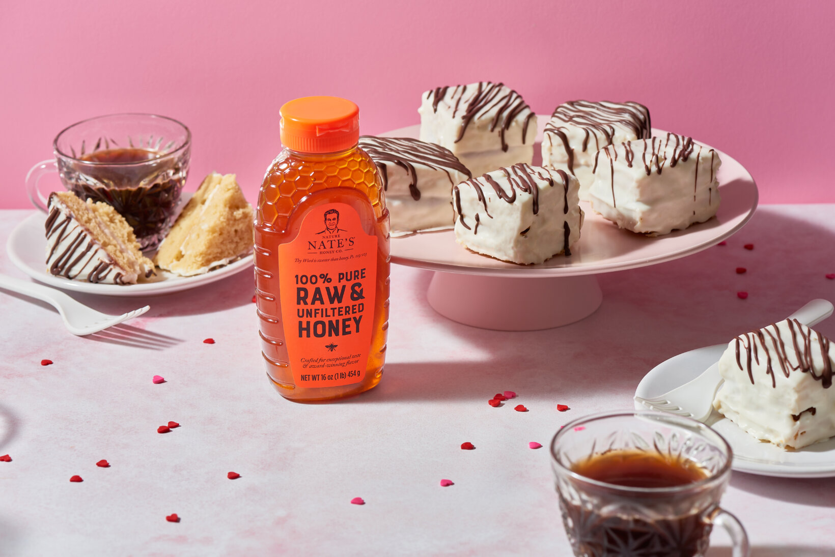 Zebra cakes displayed on a cake plate with Valentine's Day decorations, accompanied by a bottle of Nature Nate's honey.