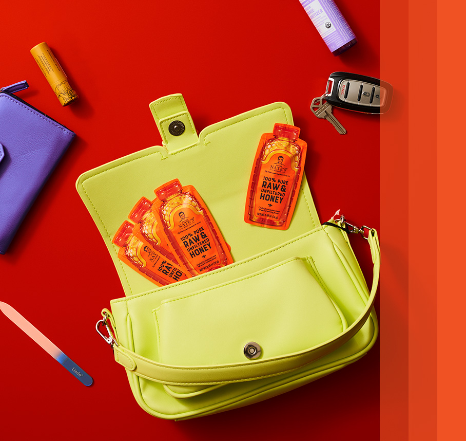 Green purse with front flap open to show four honey minis and other purse essentials: keys, wallet and chapstick.