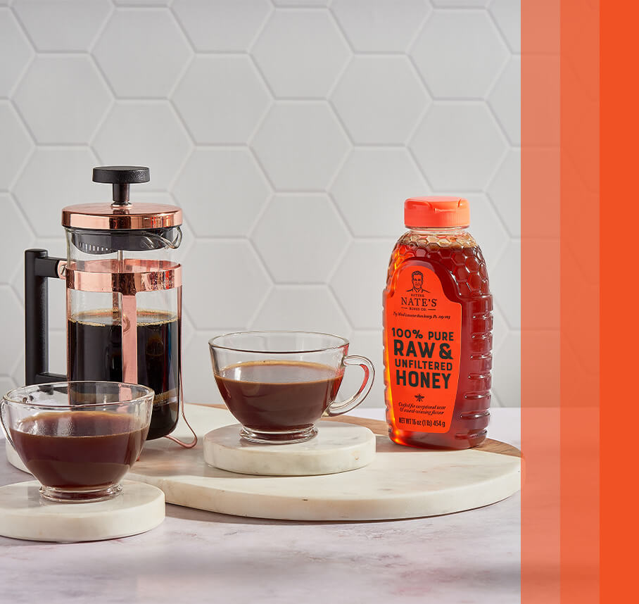 Nate’s honey bottle on counter with coffee press and cups of coffee.