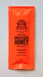 An orange packet of Nature Nate's 100% Pure Raw & Unfiltered Honey on a white background.