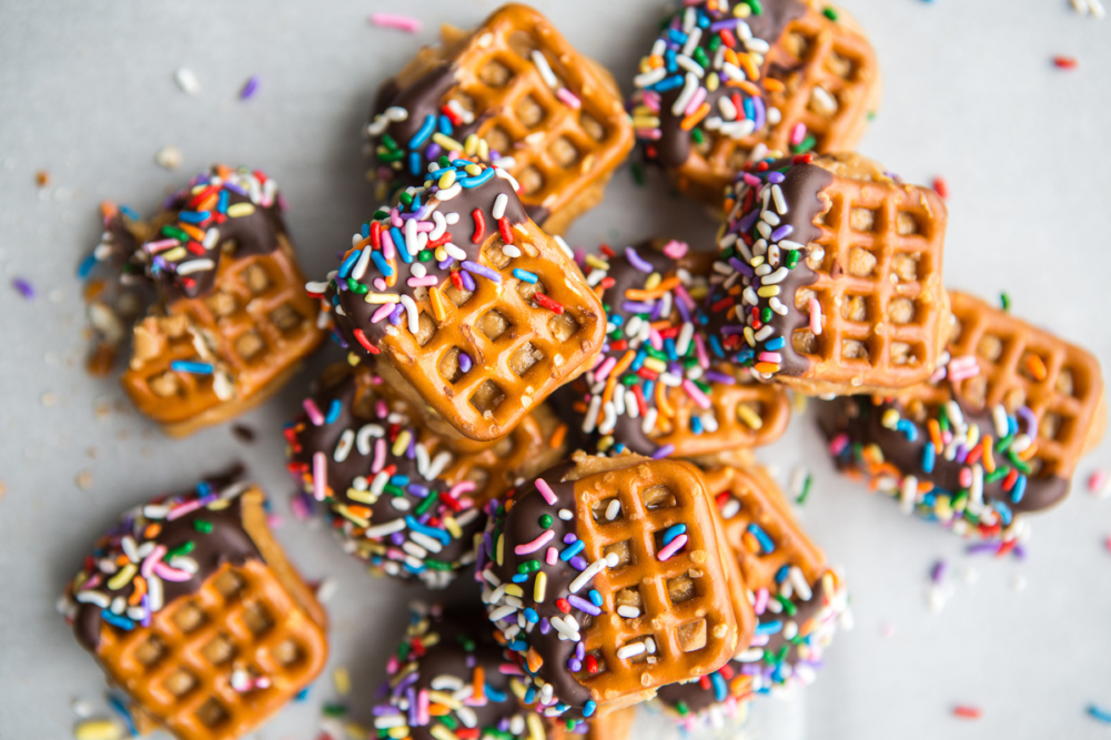 Chocolate-dipped waffle pretzels with colorful sprinkles on top.