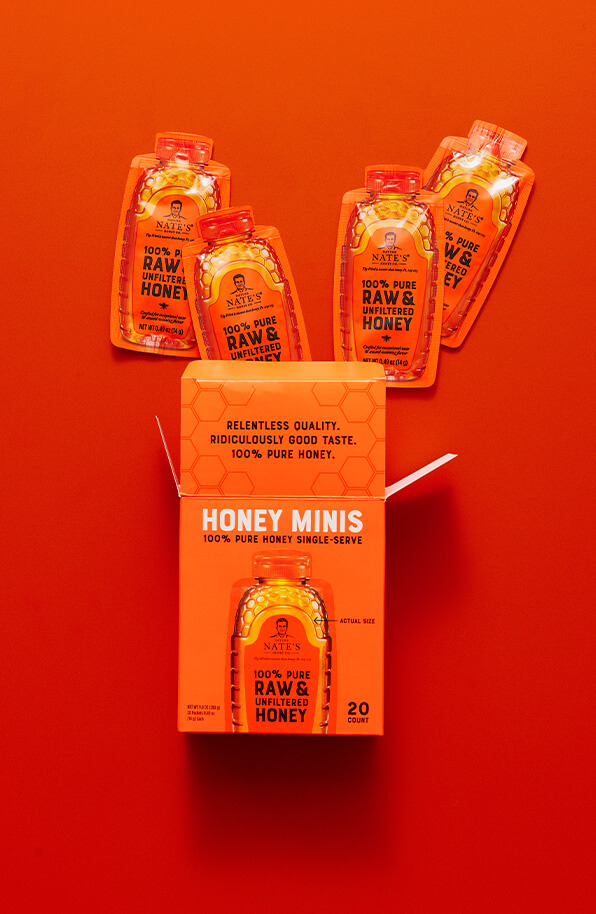Orange honey minis box with top flap open and four honey mini packets popping out the box top.