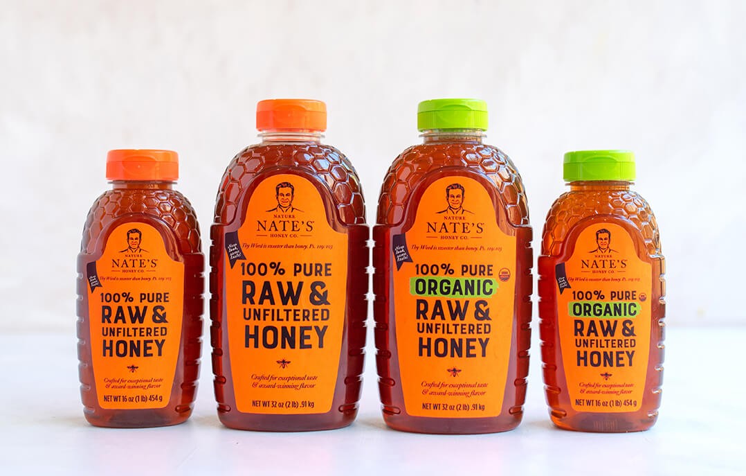 Four bottles of Nate's honey, two labeled raw & unfiltered and two organic, against a white background.