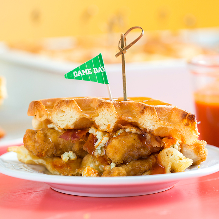 Waffle sandwich with chicken, bacon and blue cheese and a Game Day, flag on a plate, festive background.