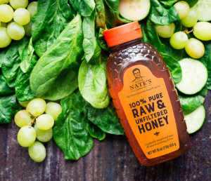 Nate's honey bottle with leafy greens and grapes; a vibe of pure, natural ingredients.