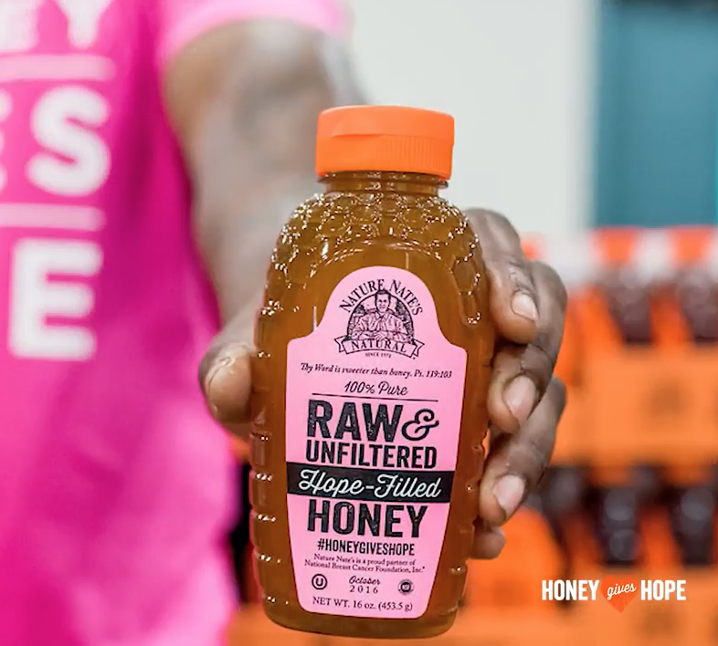 A hand presenting a bottle of Nate's honey with the text Raw & Unfiltered Hope-Filled Honey.