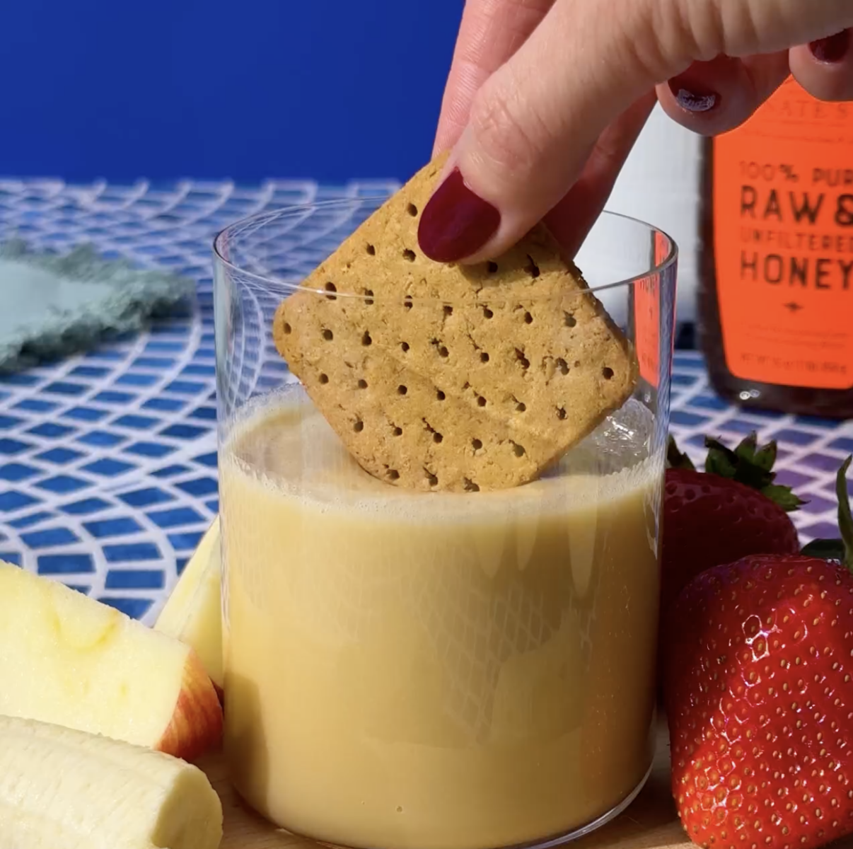 Cracker dipping into whipped honey with a Nate's honey bottle in the background.